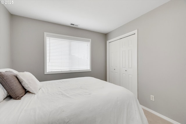 carpeted bedroom with a closet, visible vents, and baseboards