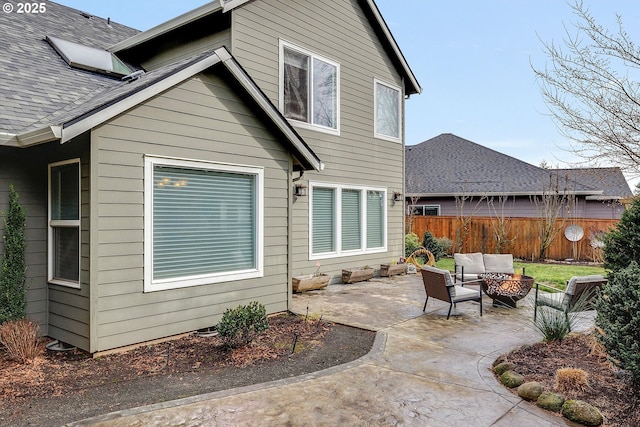 back of house featuring a shingled roof, outdoor lounge area, fence, and a patio