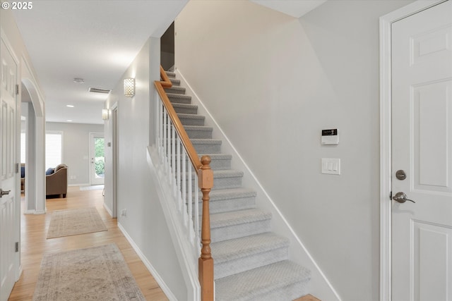 stairway with wood finished floors, visible vents, and baseboards