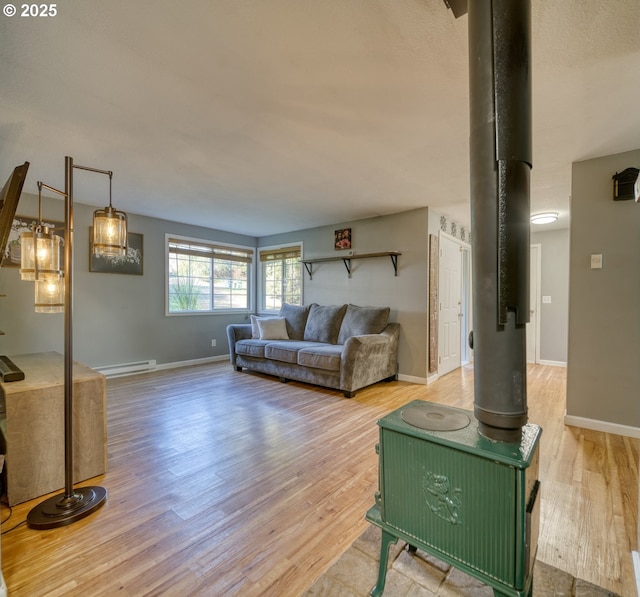 living area featuring a baseboard heating unit, light wood-style flooring, and baseboards