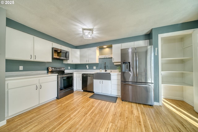 kitchen with light wood-style floors, white cabinetry, appliances with stainless steel finishes, and light countertops