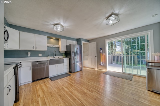 kitchen featuring light wood-type flooring, white cabinetry, appliances with stainless steel finishes, and light countertops