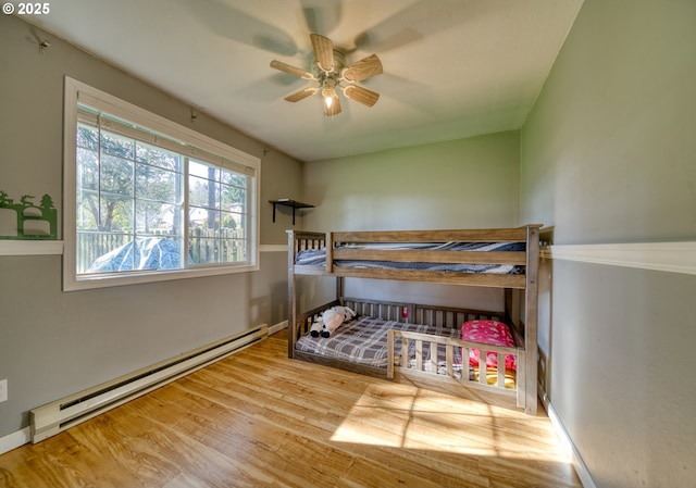 bedroom featuring baseboards, a baseboard radiator, a ceiling fan, and wood finished floors