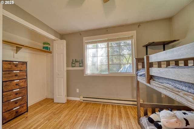 bedroom featuring baseboards, baseboard heating, and wood finished floors