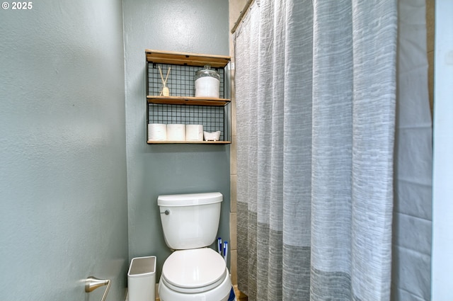 full bathroom featuring a textured wall, a shower with shower curtain, and toilet