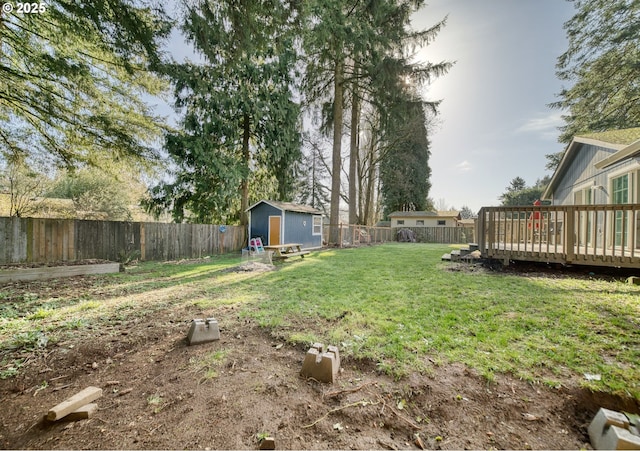 view of yard with a fenced backyard, a shed, a deck, and an outbuilding