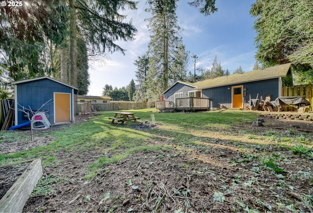 view of yard with a deck, a storage unit, an outbuilding, and a fenced backyard