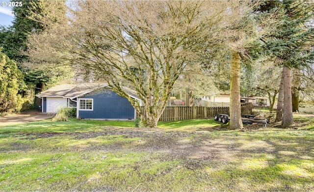 view of yard featuring an outdoor structure, fence, and an attached garage