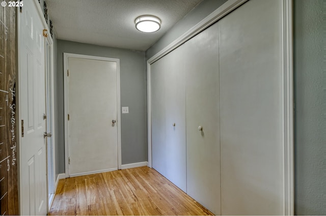 corridor featuring light wood-style flooring and a textured ceiling