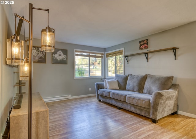 living area featuring a baseboard radiator, baseboards, and wood finished floors