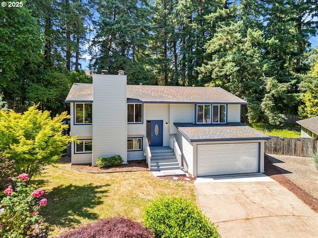 9995 SW Siuslaw Ln, Tualatin, OR 97062 - bi-level home featuring concrete driveway, roof with shingles, a chimney, and an attached garage