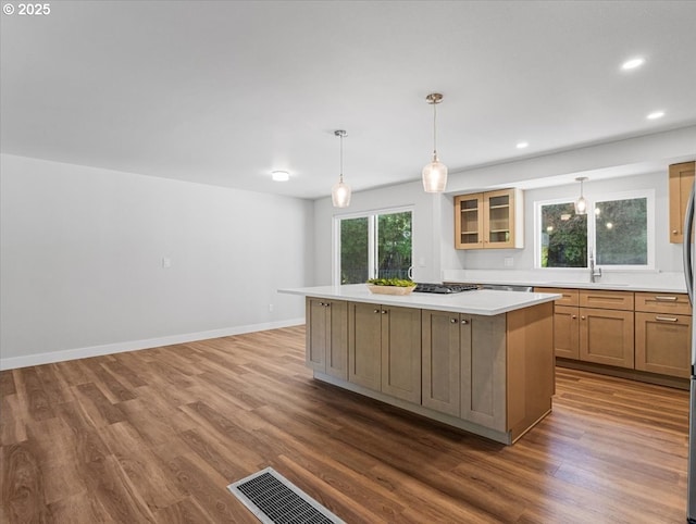 9995 SW Siuslaw Ln, Tualatin, OR 97062 - kitchen featuring a kitchen island, dark wood-type flooring, glass insert cabinets, light countertops, and recessed lighting