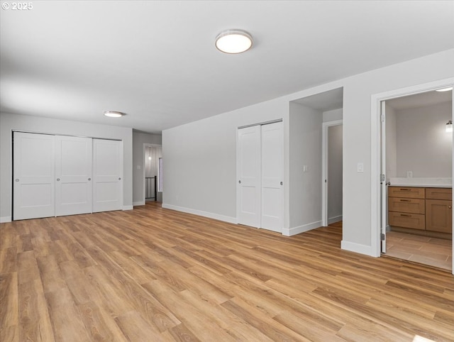9995 SW Siuslaw Ln, Tualatin, OR 97062 - unfurnished bedroom featuring two closets, light wood finished floors, and connected bathroom