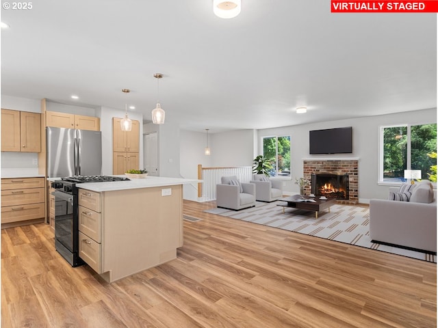 9995 SW Siuslaw Ln, Tualatin, OR 97062 - kitchen featuring black range with gas stovetop, freestanding refrigerator, open floor plan, light wood-type flooring, and light brown cabinetry