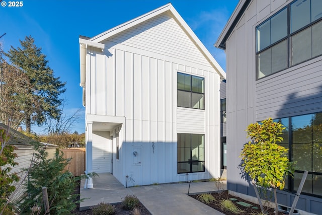 view of side of home featuring board and batten siding, a patio area, and fence