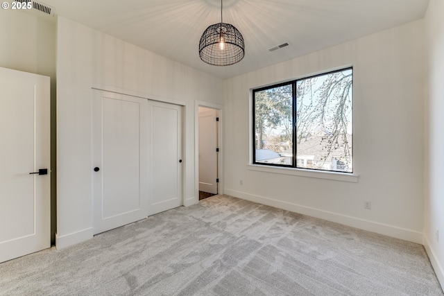 unfurnished bedroom featuring light carpet, visible vents, and baseboards