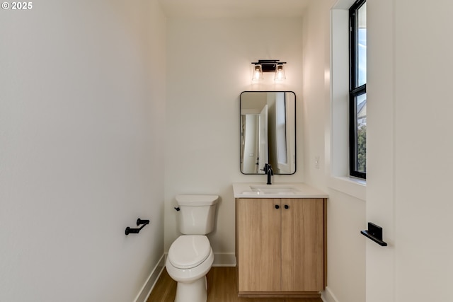 bathroom with baseboards, vanity, toilet, and wood finished floors