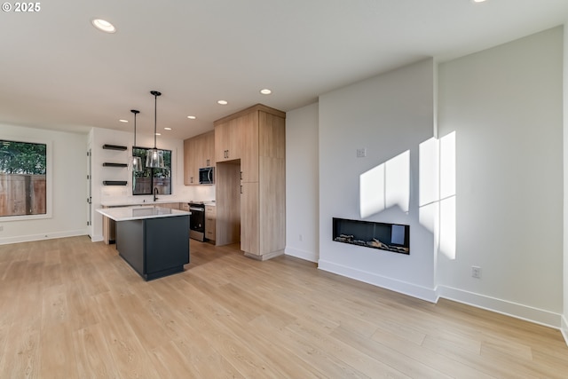 kitchen featuring light countertops, appliances with stainless steel finishes, a center island, modern cabinets, and pendant lighting