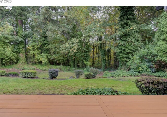wooden terrace featuring a yard and a forest view