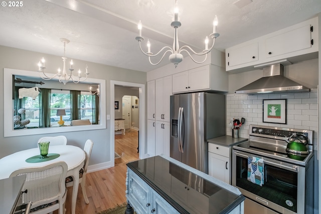 1180 16th St NE, Salem, OR 97301 - kitchen featuring a chandelier, stainless steel appliances, wall chimney range hood, and white cabinets