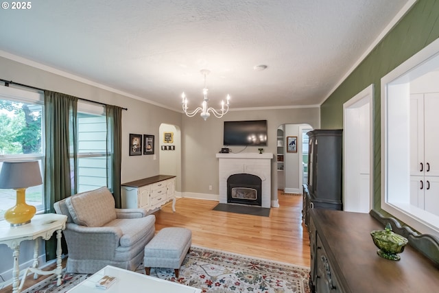 1180 16th St NE, Salem, OR 97301 - living area with arched walkways, light wood-style flooring, a chandelier, ornamental molding, and a brick fireplace