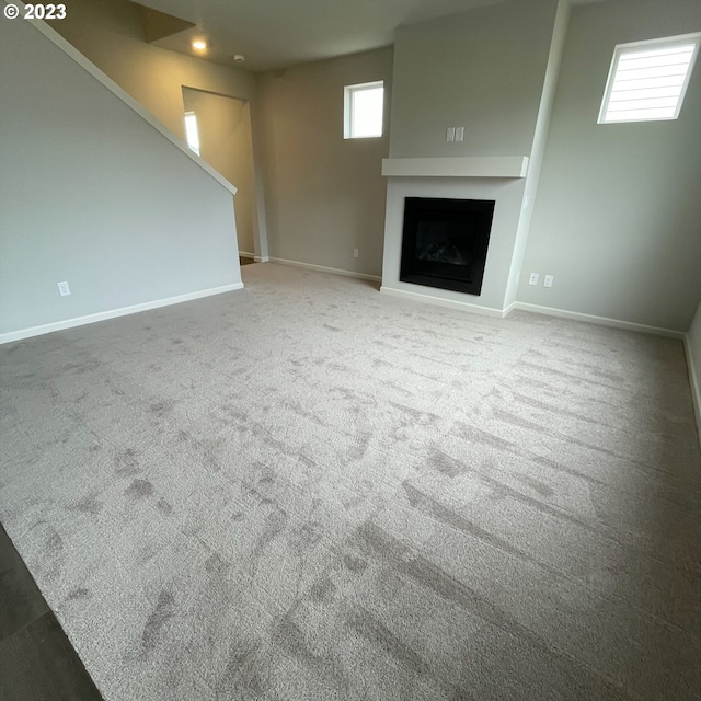 unfurnished living room with carpet, a fireplace, and baseboards