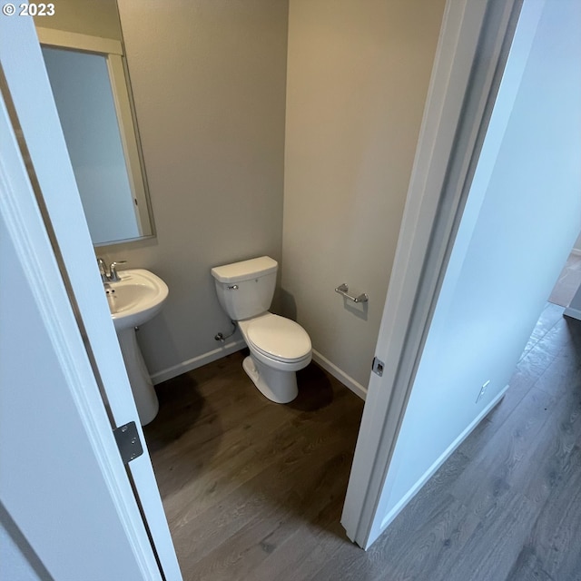 bathroom featuring toilet, a sink, baseboards, and wood finished floors