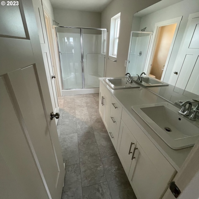 bathroom featuring double vanity, a stall shower, and a sink