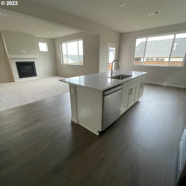 kitchen featuring visible vents, a glass covered fireplace, white cabinets, a sink, and dishwasher