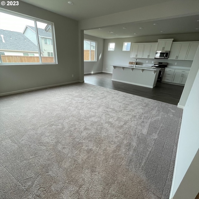 kitchen featuring stainless steel appliances, a breakfast bar, white cabinets, open floor plan, and dark colored carpet