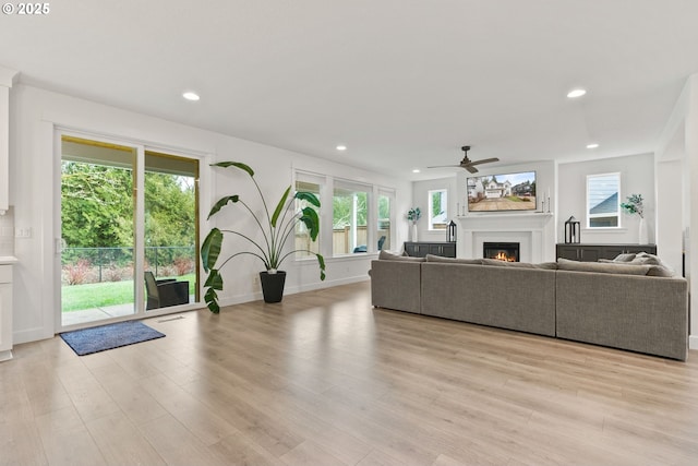 15955 SE Cherry Blossom Way, Happy Valley, OR 97015 - living area with a warm lit fireplace, ceiling fan, recessed lighting, and light wood finished floors