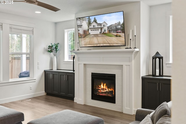 15955 SE Cherry Blossom Way, Happy Valley, OR 97015 - living area featuring wood finished floors, healthy amount of natural light, a ceiling fan, a glass covered fireplace, and recessed lighting