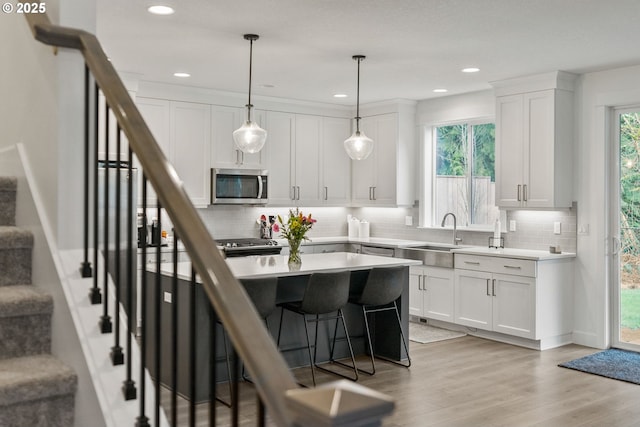 15955 SE Cherry Blossom Way, Happy Valley, OR 97015 - kitchen featuring stainless steel microwave, backsplash, light wood-style flooring, a breakfast bar area, and white cabinets
