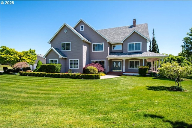 view of front facade with a chimney, a porch, a front yard, and a shingled roof