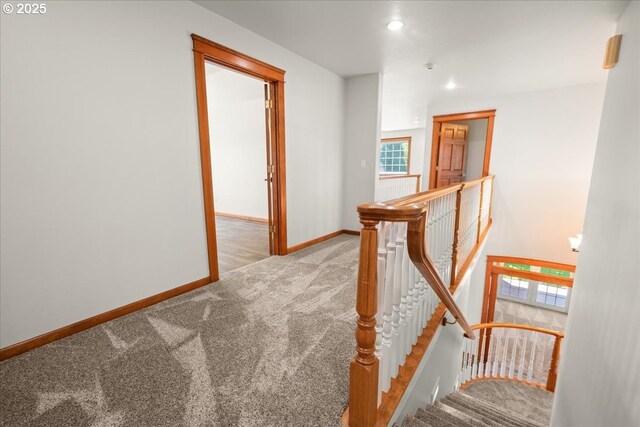 hall featuring an upstairs landing, carpet floors, baseboards, and recessed lighting