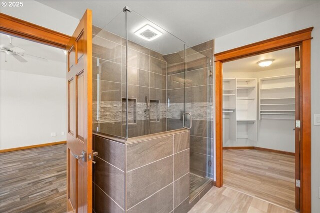 bathroom with a shower stall, a ceiling fan, wood finished floors, and baseboards