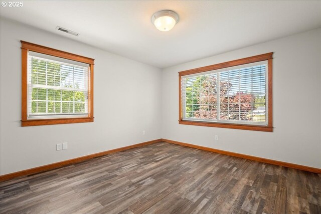unfurnished room with wood finished floors, healthy amount of natural light, and baseboards