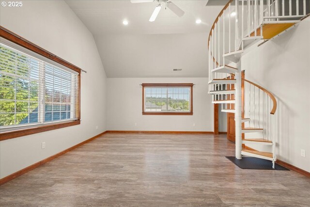 unfurnished living room with wood finished floors, stairway, ceiling fan, vaulted ceiling, and baseboards