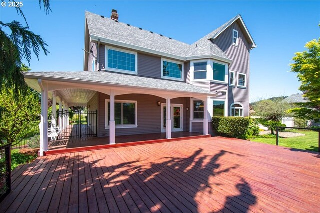 back of house featuring a chimney, a wooden deck, and a shingled roof