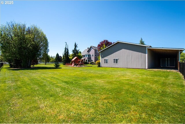 view of grassy yard with a playground and a carport