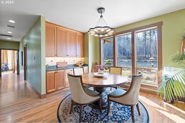 dining space with a chandelier, light wood-style flooring, and baseboards