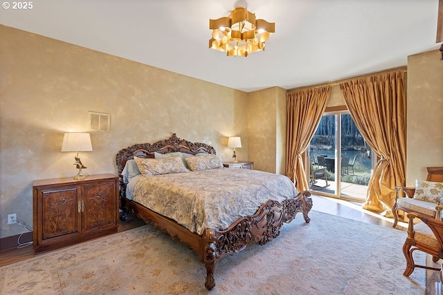 bedroom featuring access to exterior, a chandelier, and wood finished floors