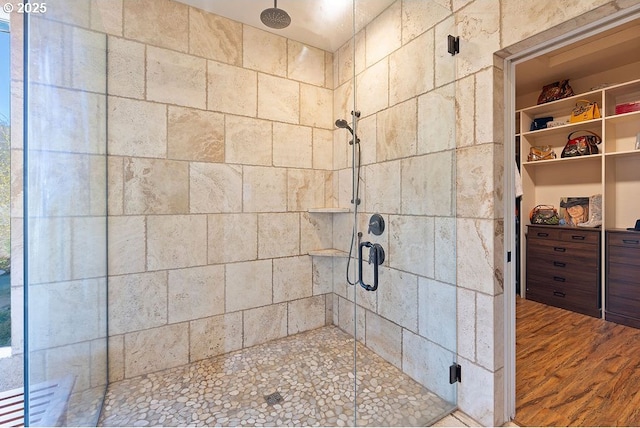full bathroom featuring a stall shower, wood finished floors, and a spacious closet