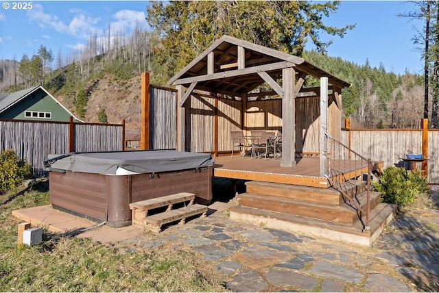 wooden terrace featuring a hot tub, a gazebo, and a fenced backyard