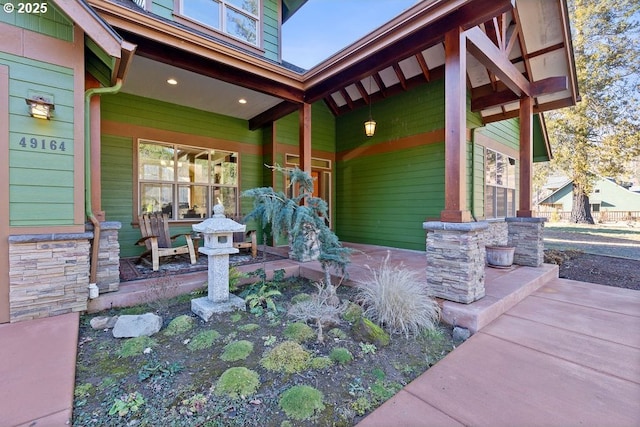 doorway to property with a porch and stone siding