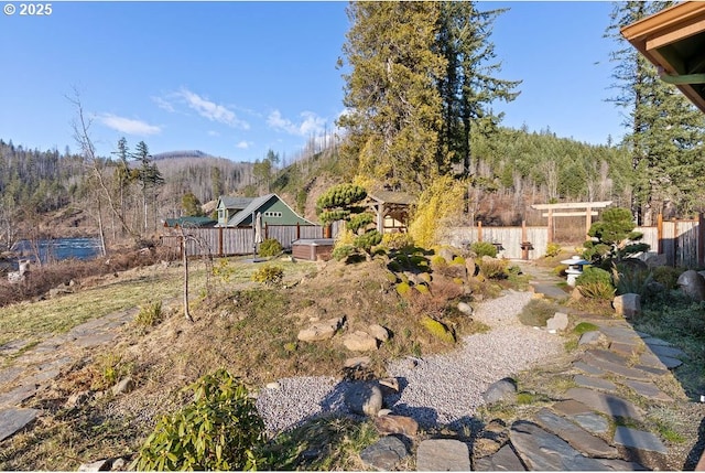 view of yard featuring fence, a mountain view, and a view of trees