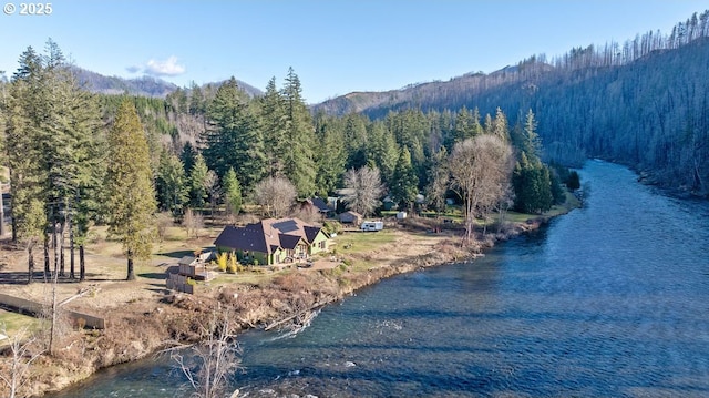 view from above of property with a heavily wooded area and a water and mountain view