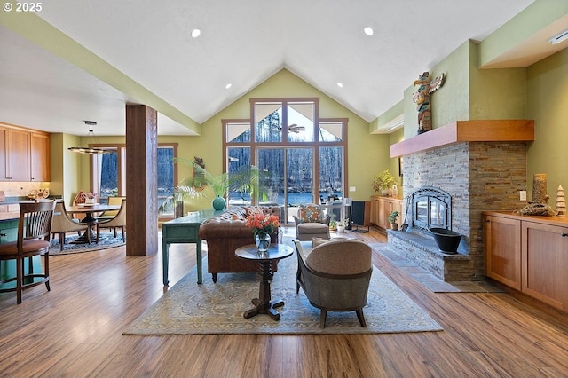 living area with a fireplace, wood finished floors, and high vaulted ceiling