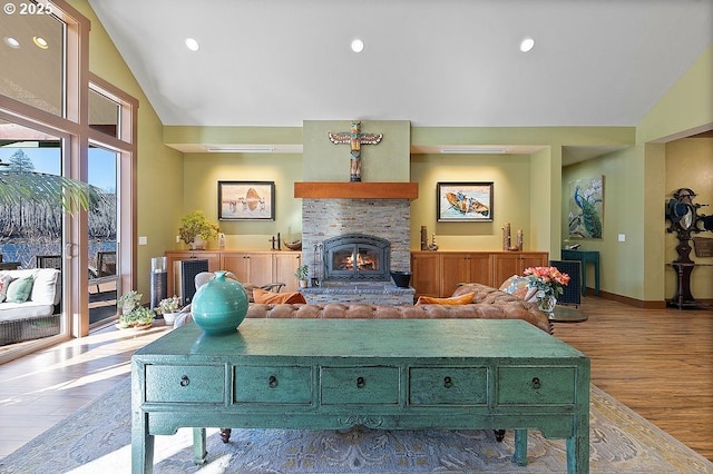 living room with wood finished floors, a stone fireplace, baseboards, high vaulted ceiling, and recessed lighting