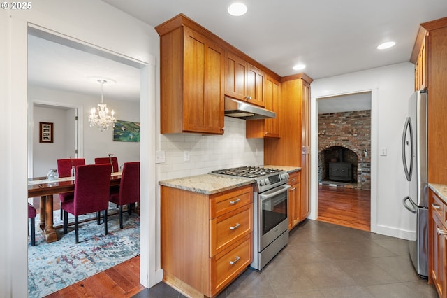 5239 Madrona St, Lake Oswego, OR 97035 - kitchen with appliances with stainless steel finishes, under cabinet range hood, tasteful backsplash, a chandelier, and light stone countertops